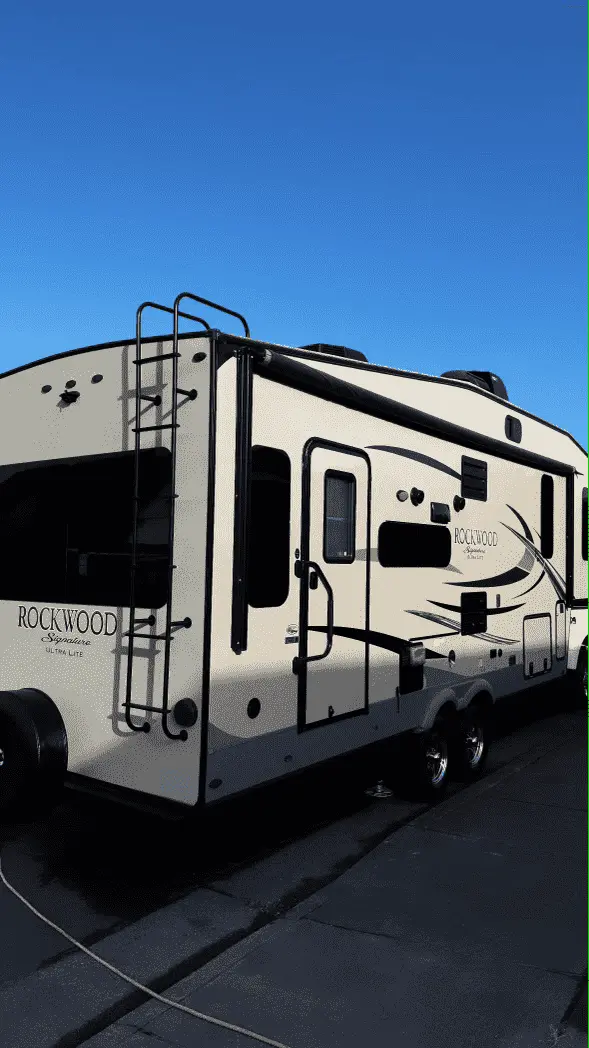 Side view of a Rockwood Signature Ultra Lite RV parked outdoors, showcasing its clean and polished exterior.